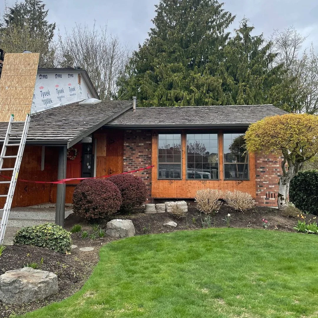 Home with boarded windows and partial roof replacement during storm damage repairs.