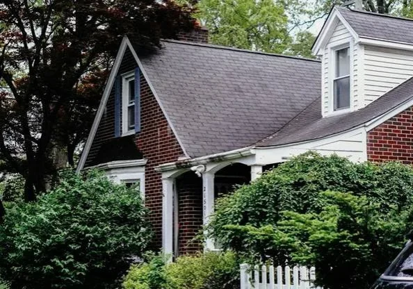 Brick home with a gray asphalt shingle roof and covered front porch
